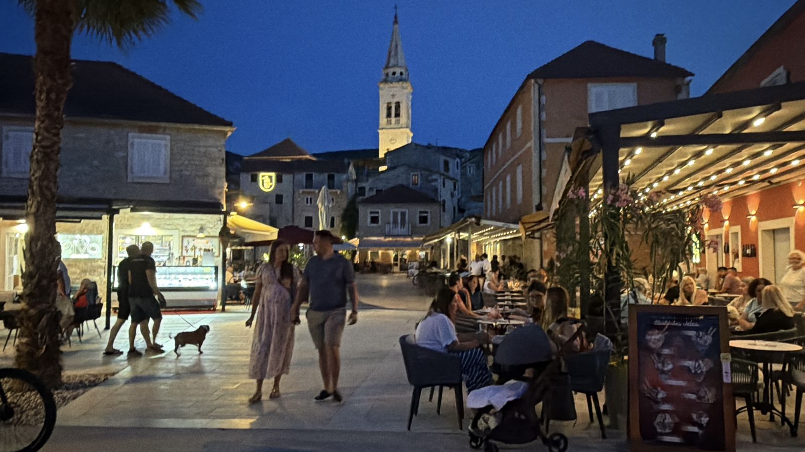 Diners at waterfront tables in a Croatian old town at dusk