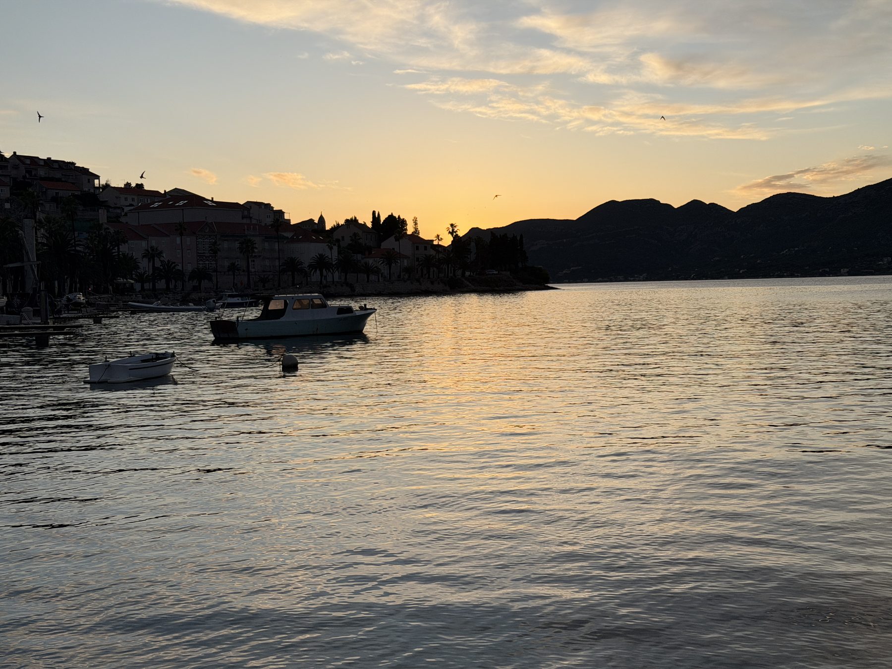 Sunset over a quiet Dalmatian harbor with small boats on still water