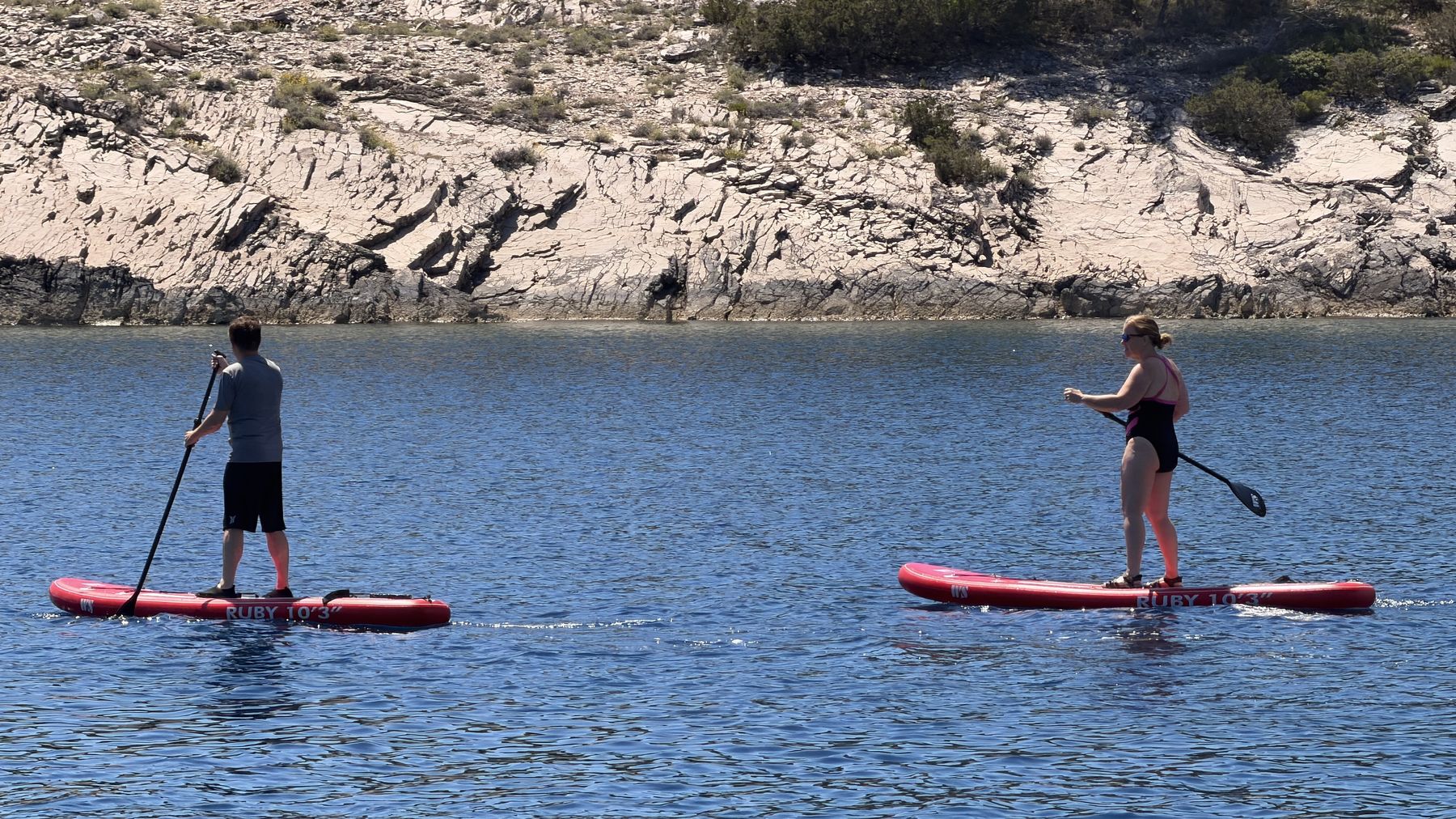 Travelers paddleboarding in a clear Adriatic cove during a swim stop