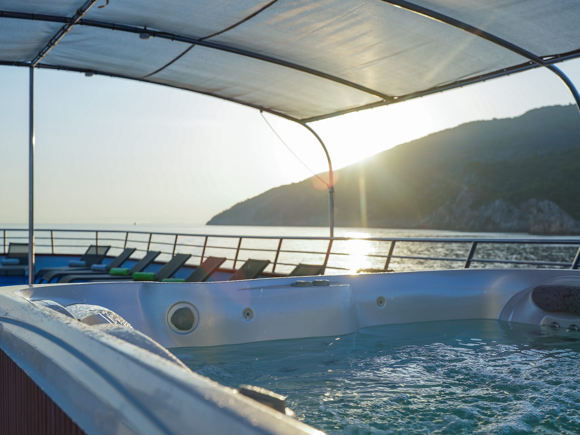 The jacuzzi on the top deck of the MS Splendid, the sun going down over an island astern