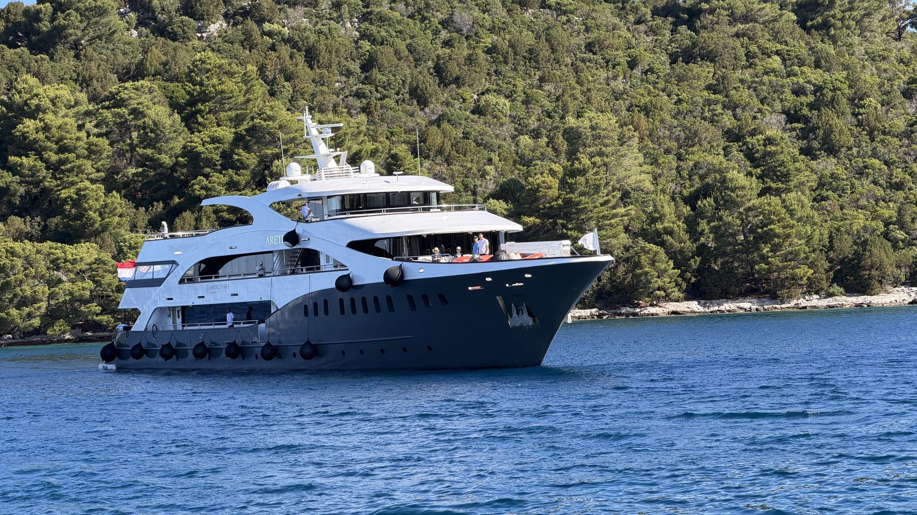 A private small ship anchored in a calm turquoise Adriatic cove off the Croatian coast