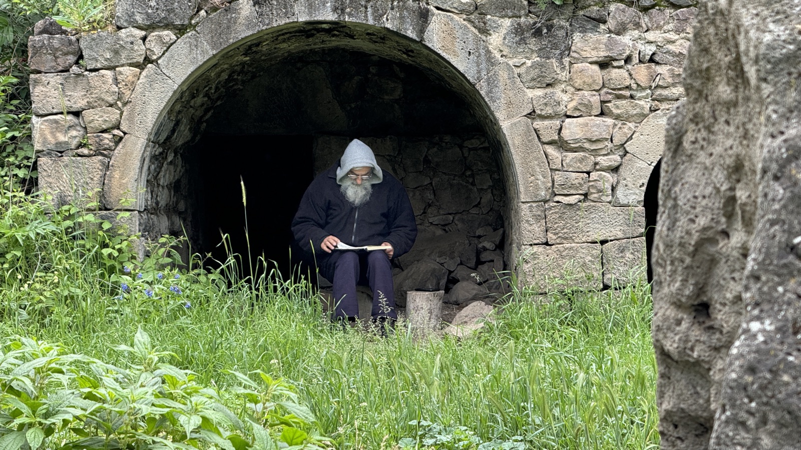 Old monk reading in stone alcove, Armenia