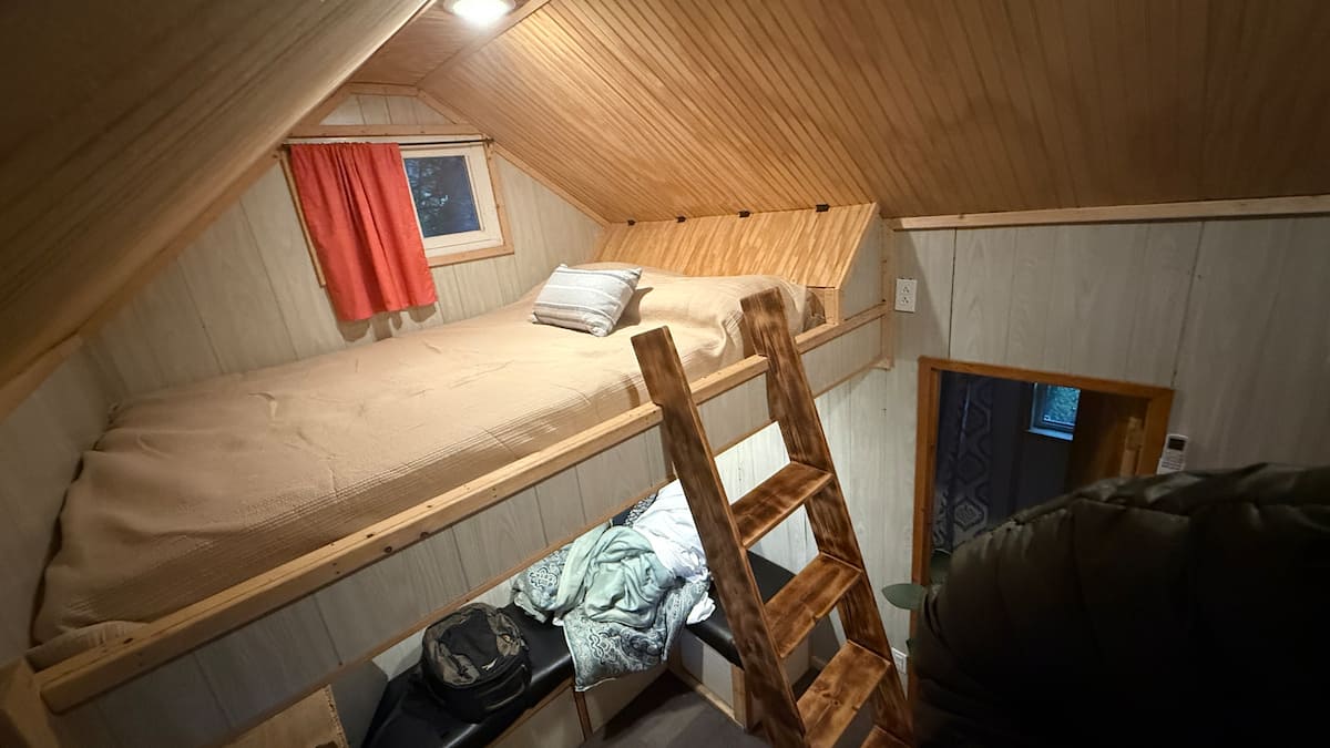 The loft bed inside Acorn Cabin, reached by a wooden ladder